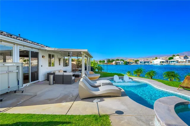 a view of a patio with couches table and chairs under an umbrella next to a yard