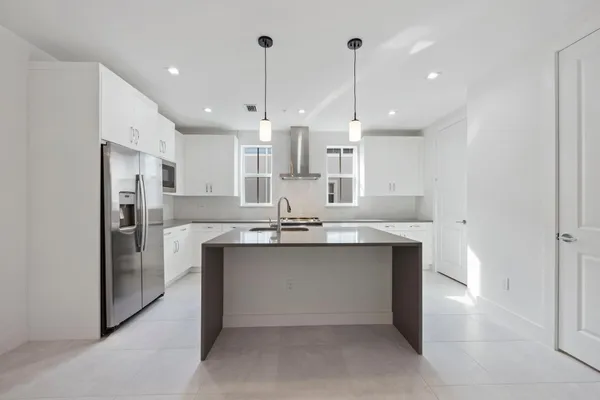 a kitchen with stainless steel appliances kitchen island a sink and a refrigerator