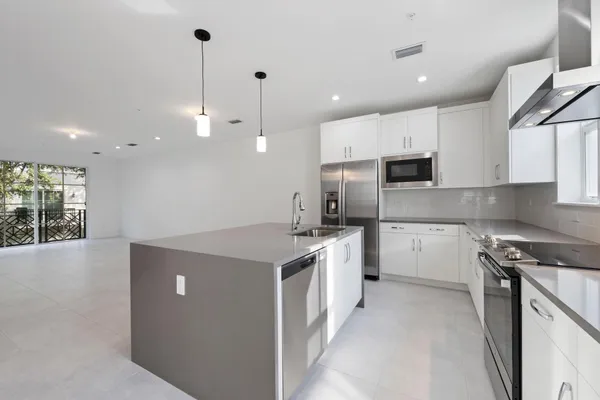 a kitchen with a sink a stove a refrigerator and white cabinets