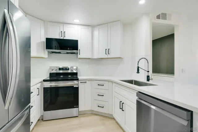 a kitchen with white cabinets and stainless steel appliances