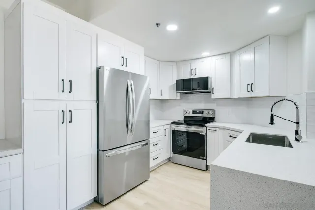 a kitchen with stainless steel appliances white cabinets and a refrigerator