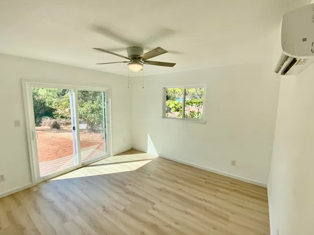 an empty room with wooden floor fan and windows