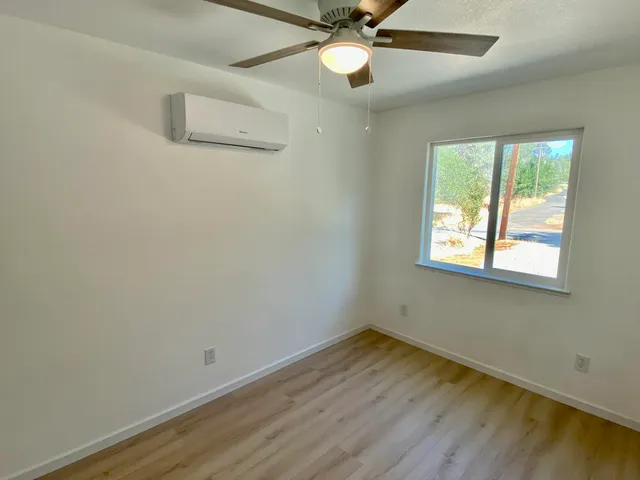 an empty room with a window and ceiling fan