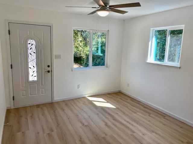 a view of an empty room with wooden floor and a window