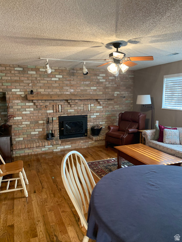 220 West Mill Road Ferron, UT 84523 - Photo 23 of 40 Living space featuring a brick fireplace with a wood mantel, wood-finish flooring, and a ceiling fan with integrated lighting