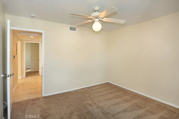 an empty room with a chandelier fan and windows