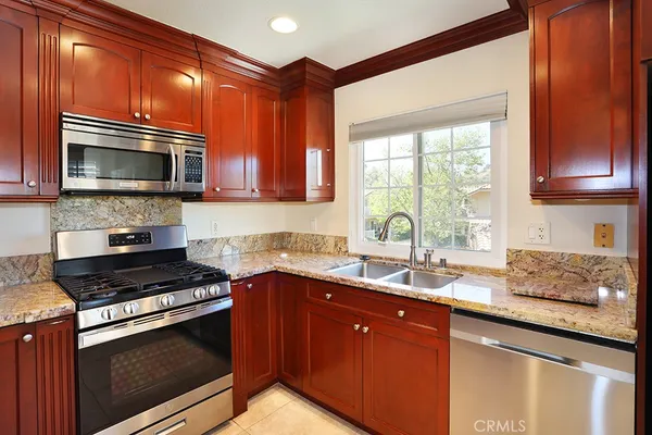 a kitchen with granite countertop a sink stove and microwave
