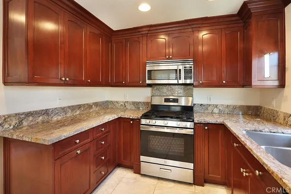 a kitchen with granite countertop wood cabinets stainless steel appliances and a counter space