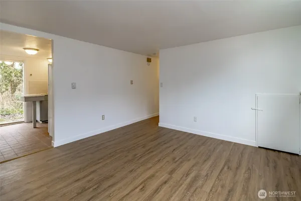 a view of an empty room with wooden floor and a window