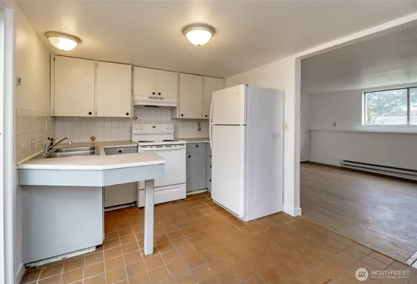 a kitchen with a sink a refrigerator and white cabinets