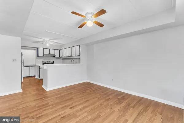 a view of kitchen and empty room with wooden floor