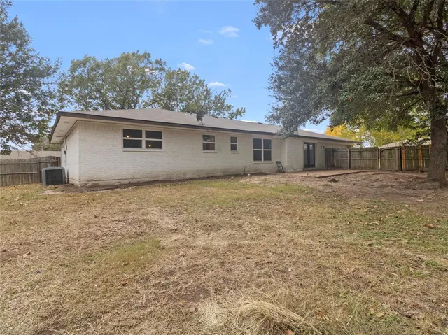 a backyard of a house with large trees and brick walls