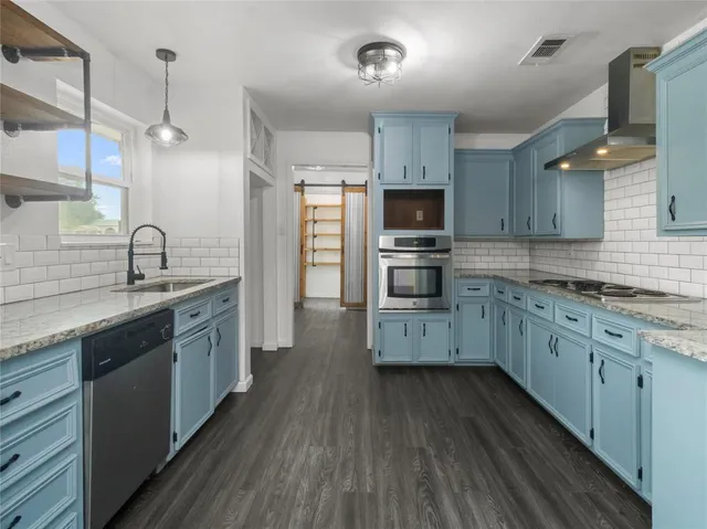 a kitchen with stainless steel appliances kitchen island granite countertop a sink cabinets and wooden floor