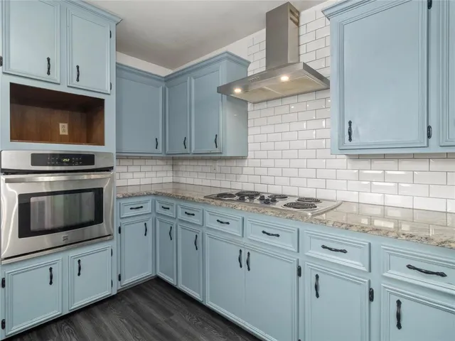 a kitchen with granite countertop white cabinets stove top oven and sink