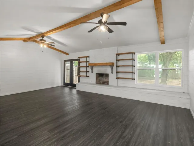 an empty room with wooden floor cabinet and windows