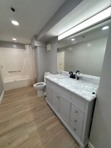 a bathroom with a granite countertop sink a toilet and a large mirror