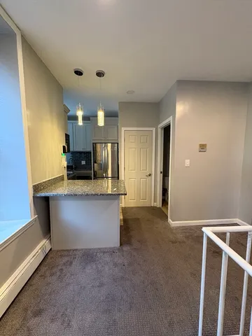 a kitchen with granite countertop a refrigerator and cabinets
