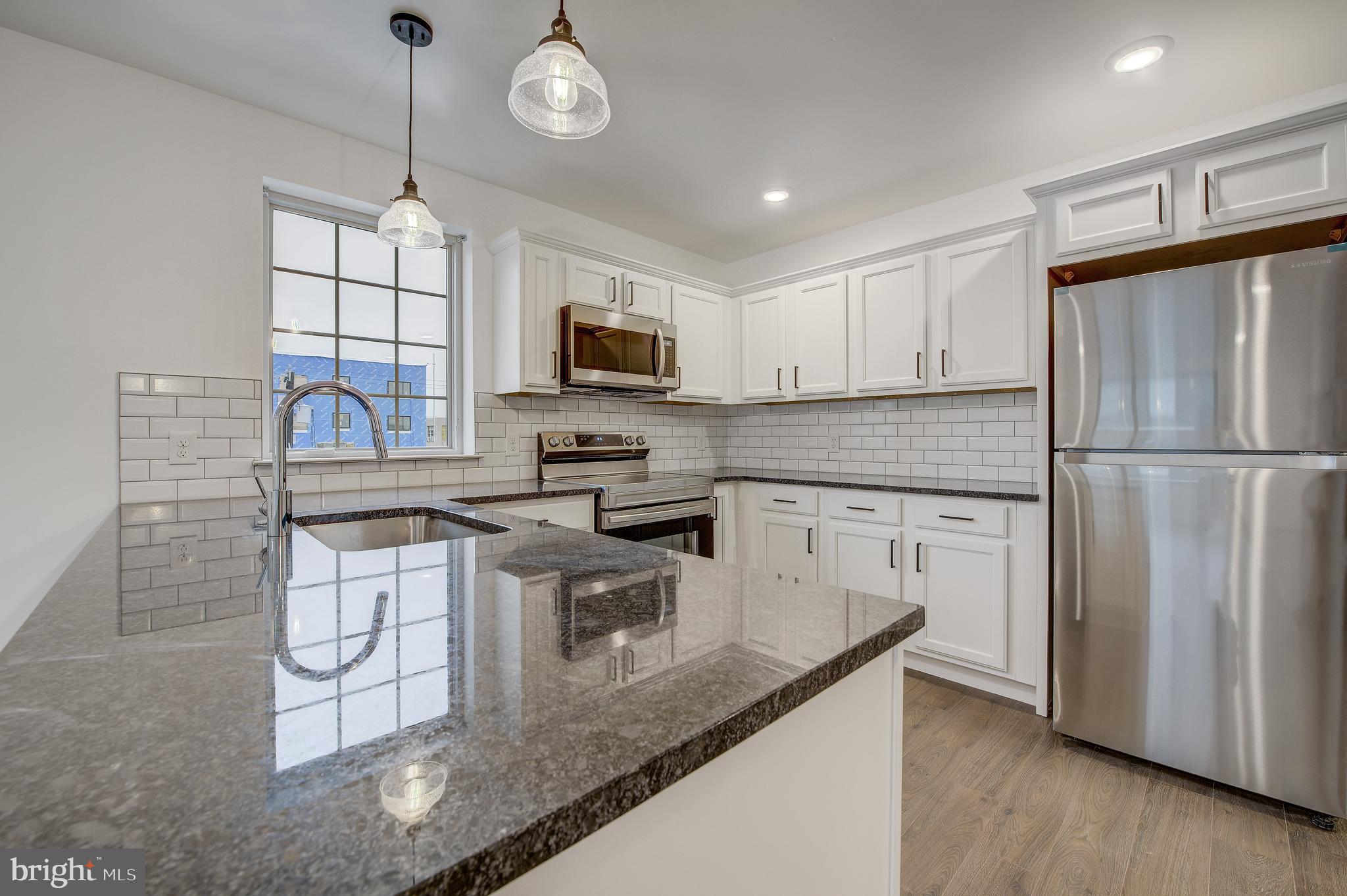 a kitchen with kitchen island granite countertop stainless steel appliances a stove microwave and refrigerator