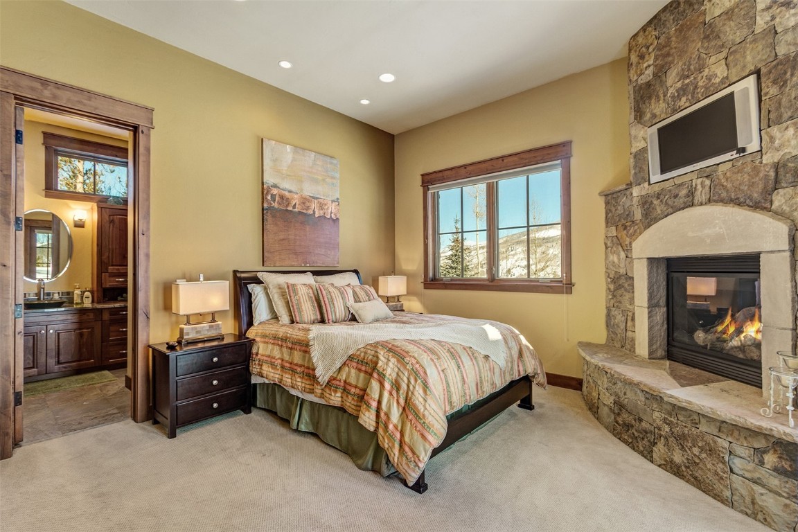 1680 Golden Eagle Road Silverthorne, CO 80498 - Photo 24 of 40 a spacious bedroom with a bed and a fireplace