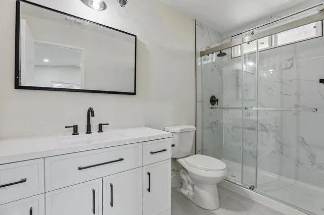 a bathroom with a toilet sink vanity and mirror