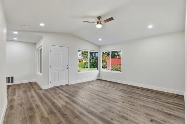 a view of an empty room with a window and wooden floor