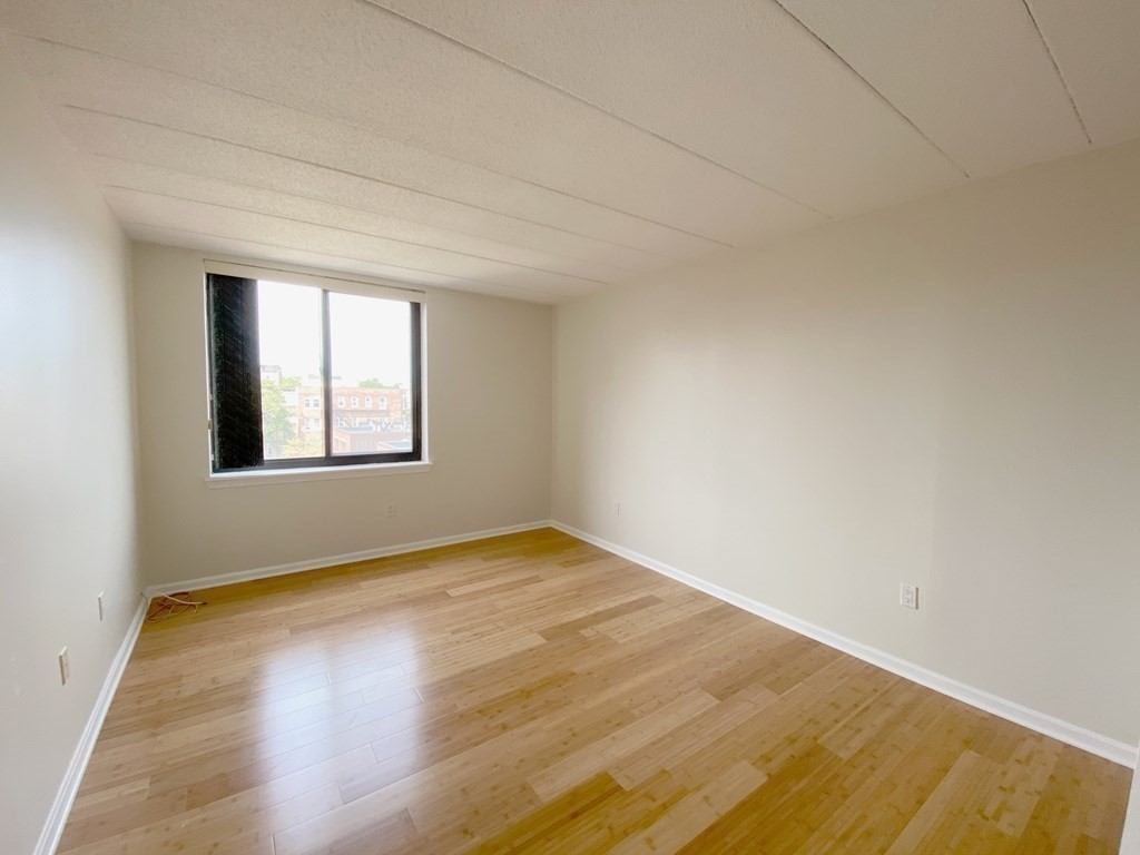 85 Brainerd Road, Unit 503 Boston, MA 02134 - Photo 8 of 21 an empty room with wooden floor and windows