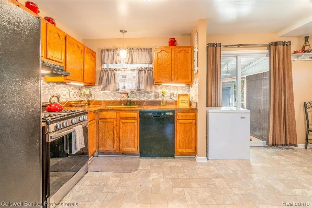 3582 Swanson Street Wayne, MI 48184 - Photo 11 of 30 Kitchen featuring black appliances, pendant lighting, decorative backsplash, stone finish flooring, and under cabinet range hood