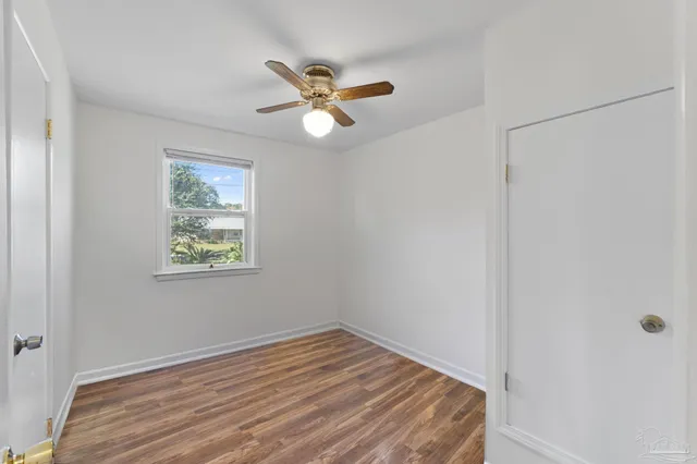 a view of empty room with wooden floor and fan