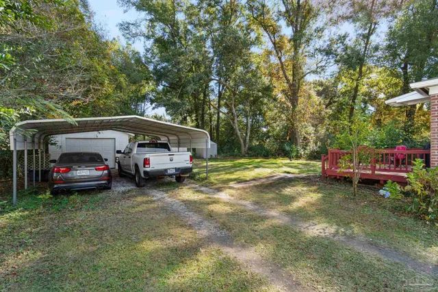 a view of a car parked in a yard with large trees
