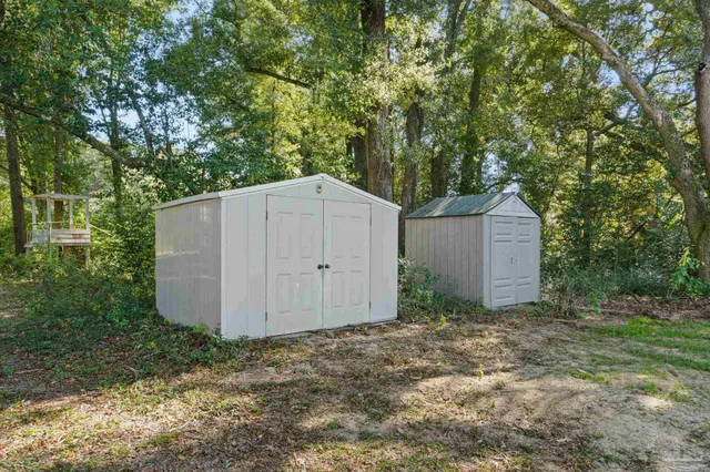 a backyard of a house with plants and large tree