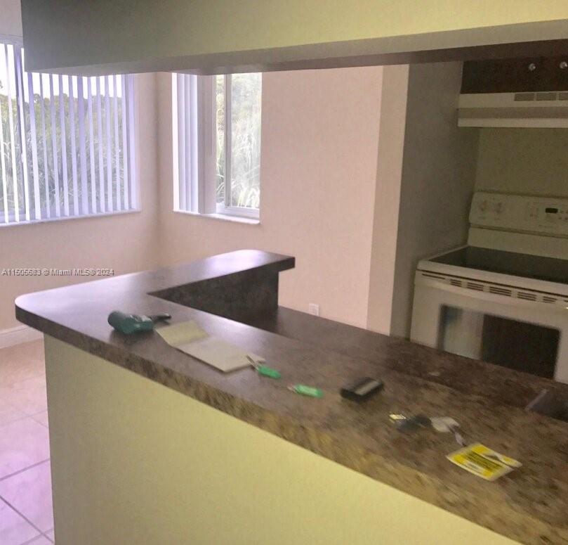 5686 Rock Island Road, Unit 134 Tamarac, FL 33319 - Photo 4 of 21 a kitchen with granite countertop a sink a stove and a microwave