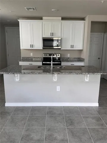 a view of kitchen with stainless steel appliances granite countertop a sink a stove a microwave and a refrigerator