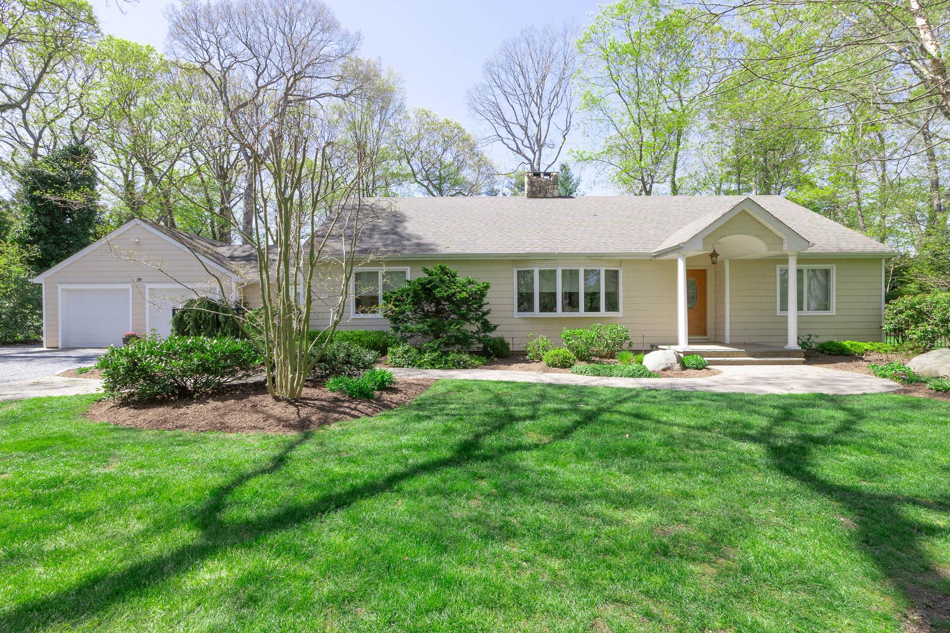 Single story home with a shingled roof, a front yard, driveway, and a chimney