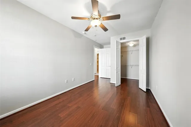 an empty room with wooden floor ceiling fan and stairs