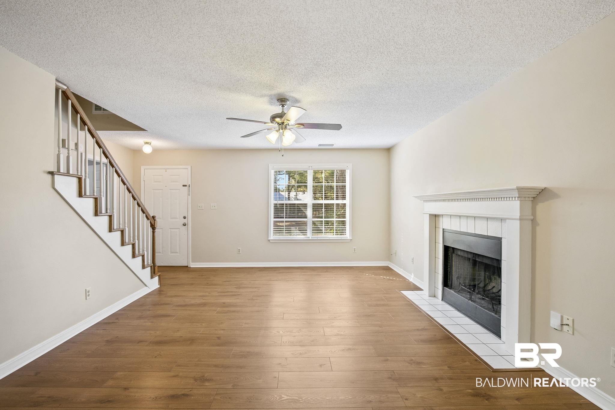 359 Ridgewood Drive Daphne, AL 36526 - Photo 16 of 73 Unfurnished living room with a tiled fireplace, a textured ceiling, light hardwood / wood-style flooring, and ceiling fan