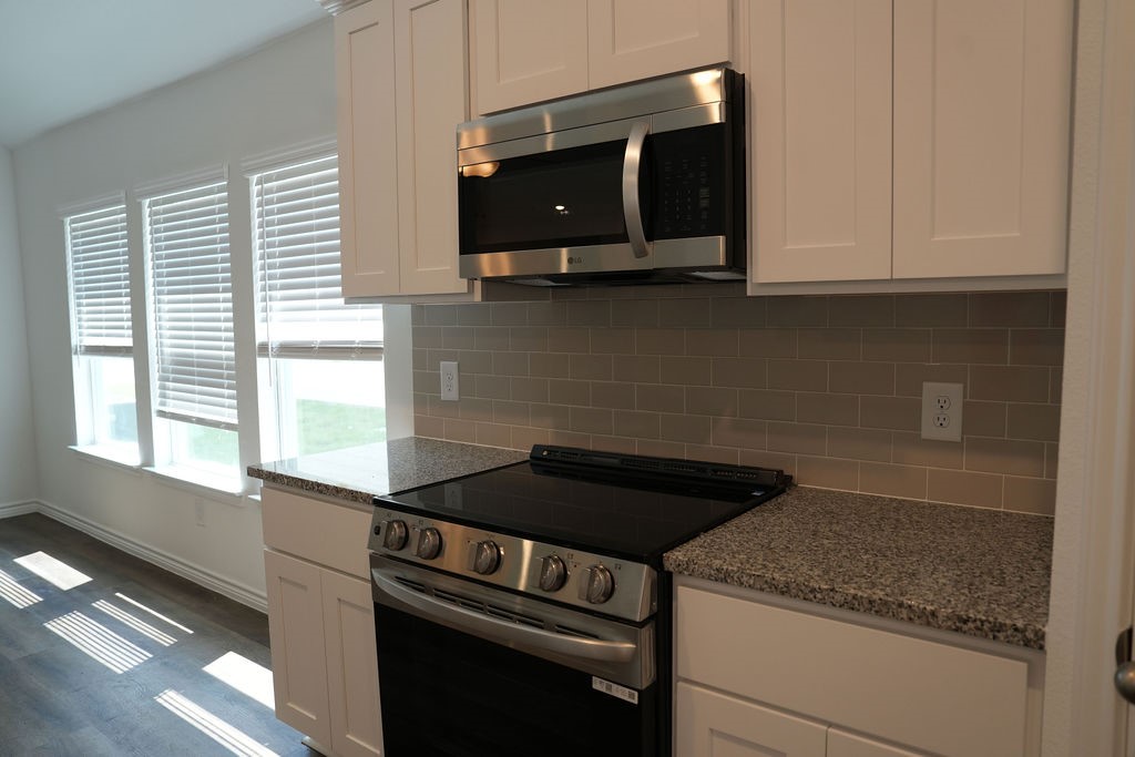 807 Stoney Point Lane Dayton, TX 77535 - Photo 5 of 19 a kitchen with granite countertop white cabinets and black appliances