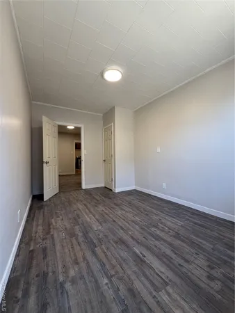 a view of an empty room with wooden floor and closet