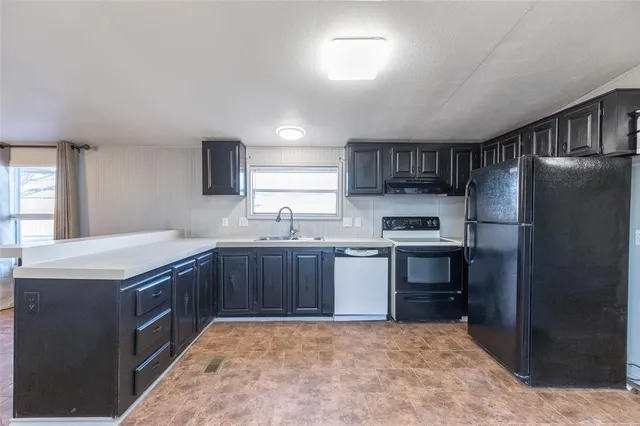 a kitchen with granite countertop a refrigerator and a stove top oven