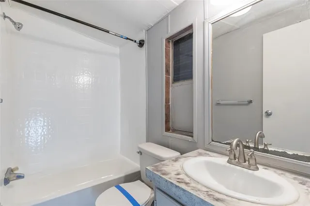 a bathroom with a granite countertop sink a toilet and shower