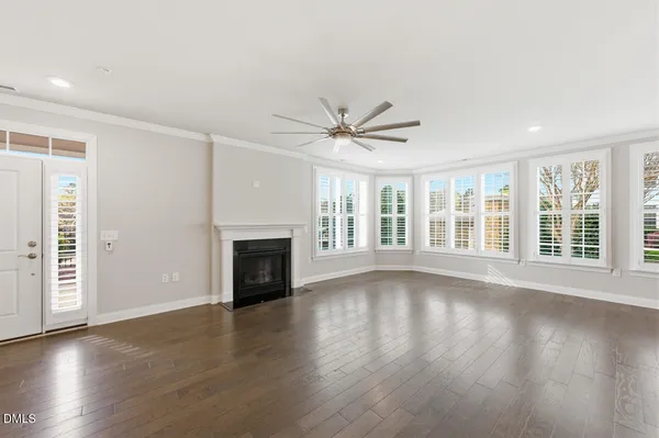 a view of an empty room with wooden floor and a fireplace