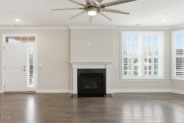 a view of an empty room with wooden floor fireplace and a window