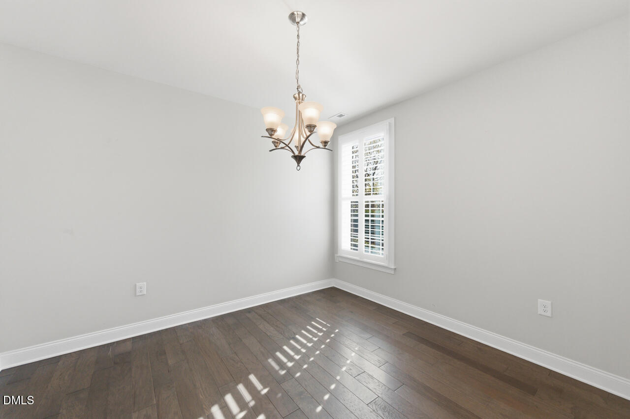 10210 Sablewood Drive, Unit 114 Raleigh, NC 27617 - Photo 15 of 28 an empty room with wooden floor chandelier and windows