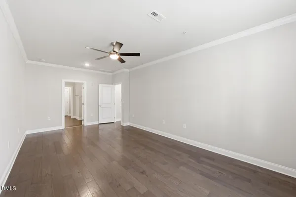 an empty room with wooden floor and ceiling fan