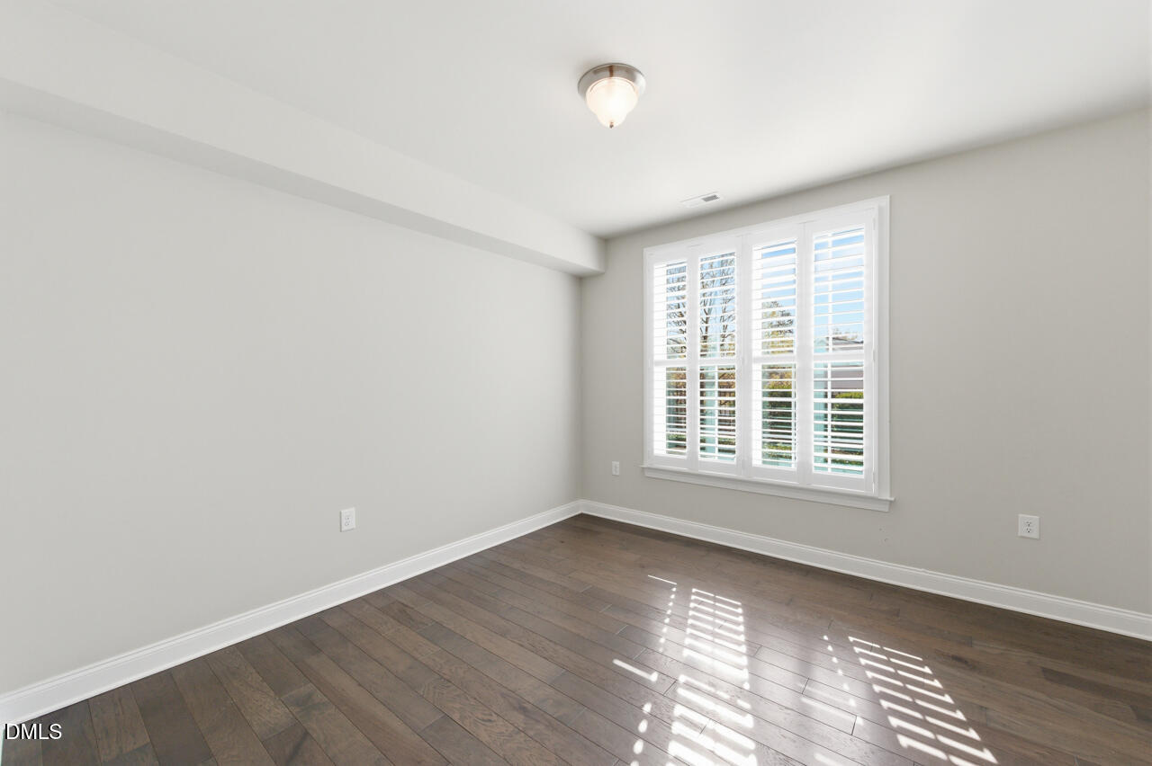 10210 Sablewood Drive, Unit 114 Raleigh, NC 27617 - Photo 22 of 28 a view of an empty room with wooden floor and a window
