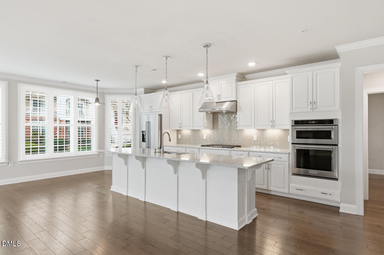 10210 Sablewood Drive, Unit 114 Raleigh, NC 27617 - Photo 6 of 28 a kitchen with stainless steel appliances granite countertop a sink a stove a refrigerator and white cabinets with wooden floor