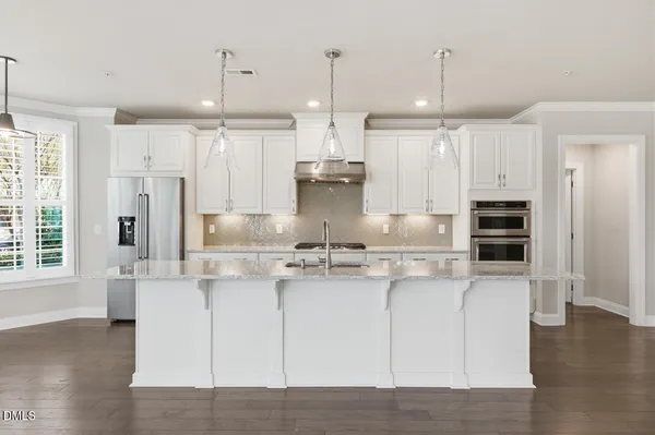 a kitchen with kitchen island stainless steel appliances a stove a refrigerator a center island and wooden floor
