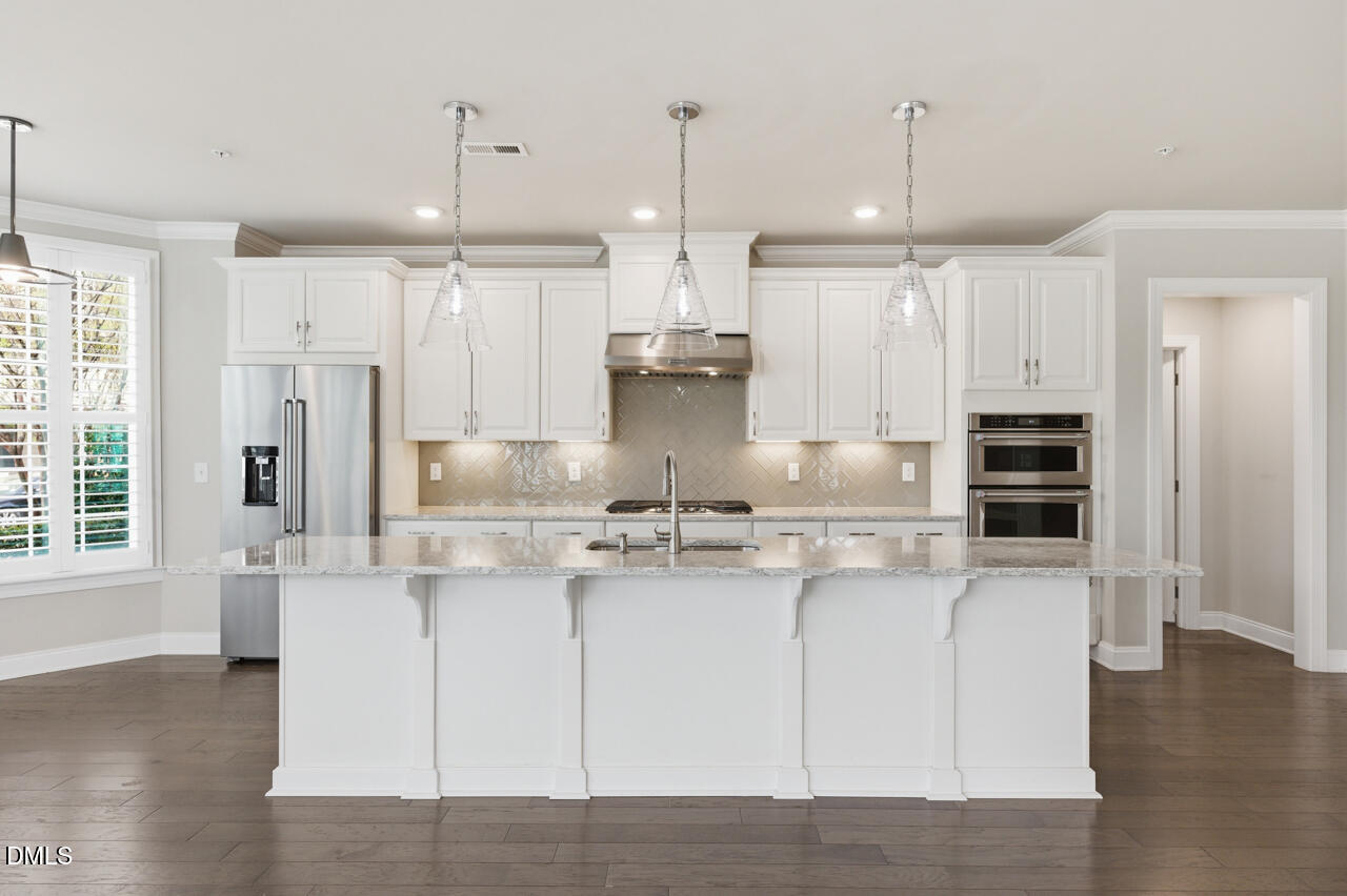 10210 Sablewood Drive, Unit 114 Raleigh, NC 27617 - Photo 7 of 28 a kitchen with kitchen island stainless steel appliances a stove a refrigerator a center island and wooden floor