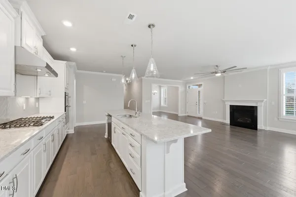 a large white kitchen with a stove a sink a refrigerator and a fireplace