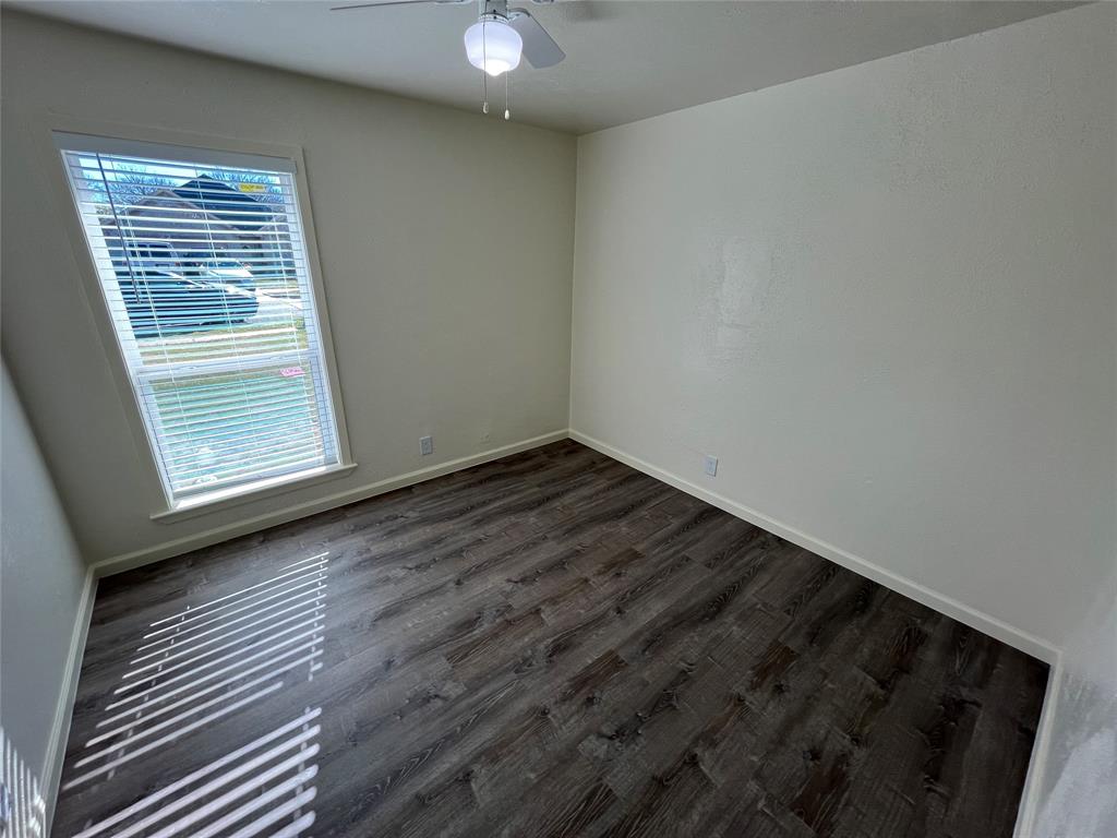 10135 Kittyhawk Lane Dallas, TX 75217 - Photo 12 of 17 Empty room featuring dark wood-style flooring and baseboards
