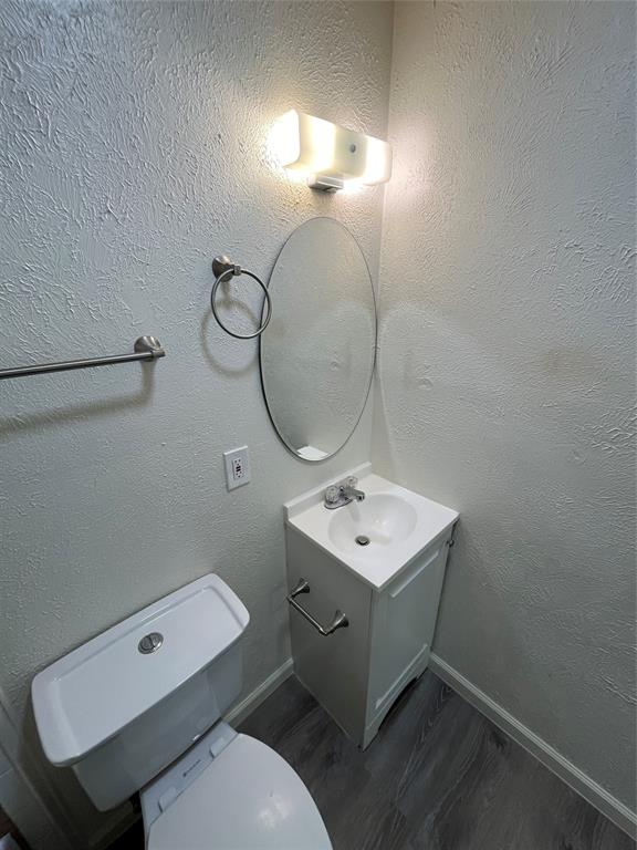 10135 Kittyhawk Lane Dallas, TX 75217 - Photo 5 of 17 Half bathroom featuring a textured wall, vanity, and dark wood-style flooring